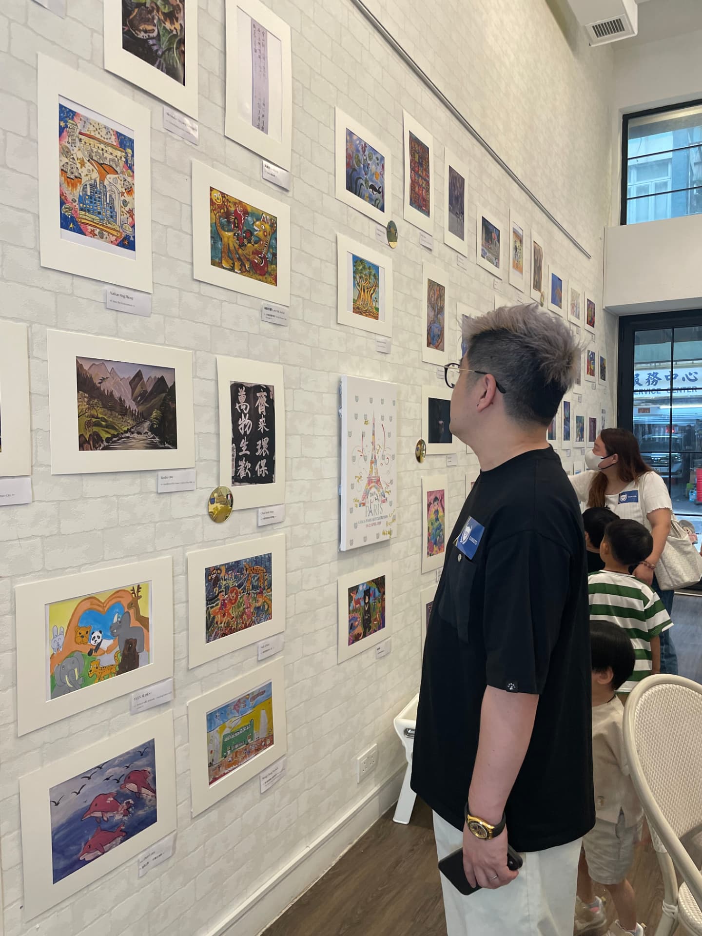 訪客於 GASCA 展覽欣賞整幅牆的兒童畫作及書法作品